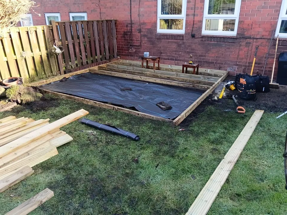 New deck frame being built over membrane beside the brick house