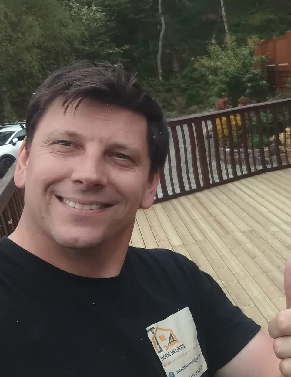 Johnny Stott wearing his Home Helpers work shirt beside a deck